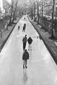 853927 Afbeelding van enkele schaatsers op de bevroren Nieuwegracht te Utrecht.